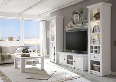 a living room filled with furniture and a flat screen tv on top of a white entertainment center