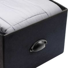 a close up of a bed with a white pillow and black box on it's side