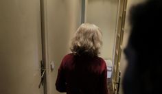 a woman standing in front of a mirror looking at her reflection on the door way