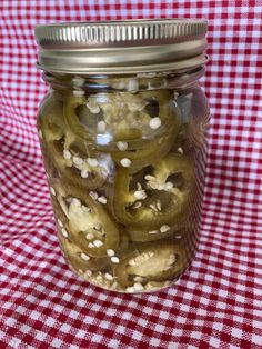 pickles in a jar on a red and white checkered tablecloth