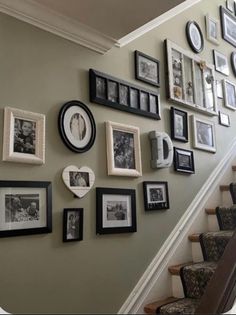 a staircase with many pictures and frames on the wall next to it's handrail