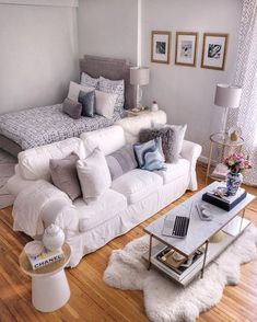 a living room filled with white furniture and lots of pillows on top of it's couches