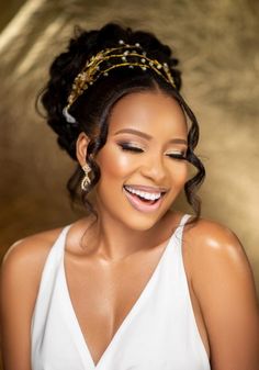 a smiling woman wearing a white dress and gold headpiece