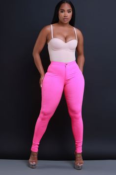 a woman wearing pink pants and a white top is posing for the camera with her hands on her hips