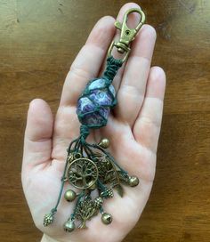 a hand holding a key chain with charms on it