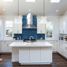 a large kitchen with white cabinets and blue tile backsplashes on the walls