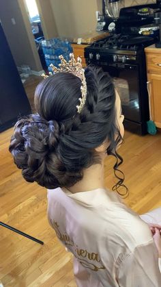 a woman is sitting on the floor with her hair in a bun and wearing a tiara