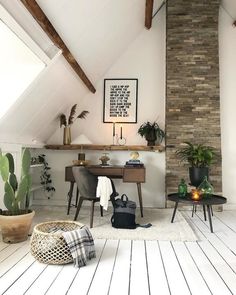 a room with some plants and a desk in the corner on top of a wooden floor