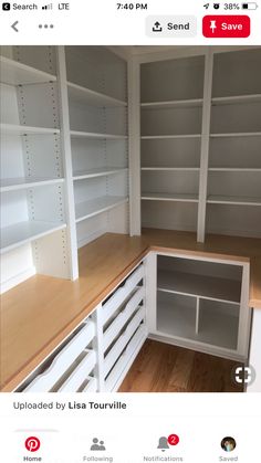 an empty room with white shelving and wood flooring on the bottom shelf, next to a wooden counter top