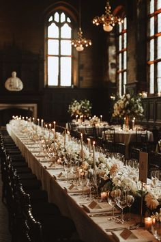 a long table is set with candles and flowers for an elegant wedding reception in the great hall