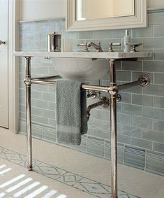 a white sink sitting under a bathroom mirror next to a wall mounted faucet