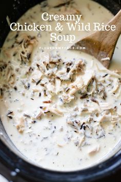 creamy chicken and wild rice soup in a crock pot with a wooden spoon on the side