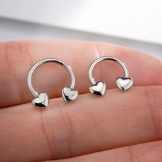 two heart shaped nose rings are shown in the palm of a person's hand