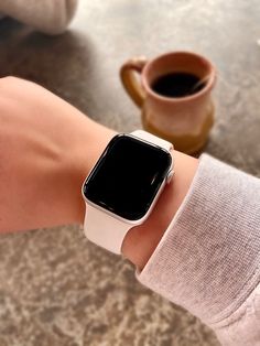 an apple watch on someone's wrist with a cup of coffee in the background