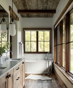 a bathroom with wooden floors and white walls, along with a large tub in the center