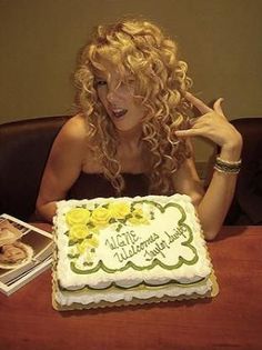 a woman sitting at a table in front of a cake with the words happy birthday written on it