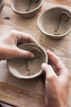 a person is making bowls with their hands on the wooden table and they are holding something in front of them