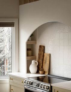 a stove top oven sitting inside of a kitchen next to a wooden cutting board and window