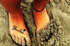 a person's feet in the sand with their name written on them and two hearts