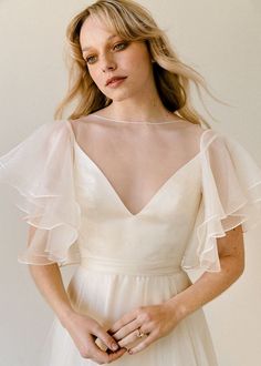 a woman in a white dress is posing for the camera with her hands on her hips