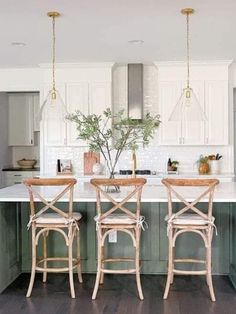 a kitchen with white cabinets and green counter tops, two stools at the island