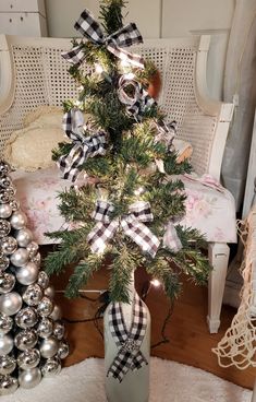 a decorated christmas tree in a vase next to ornaments and a table with a chair