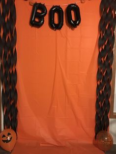 an orange backdrop with black letters and balloons in the shape of boos on it