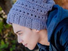 a woman wearing a crocheted hat looks down at her cell phone while outside