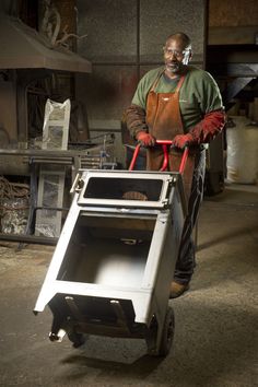 a man in overalls and safety glasses pushing a cart