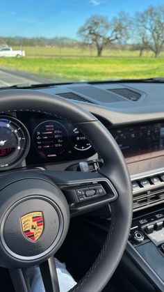 the steering wheel and dashboard of a porsche cayenne with an open field in the background