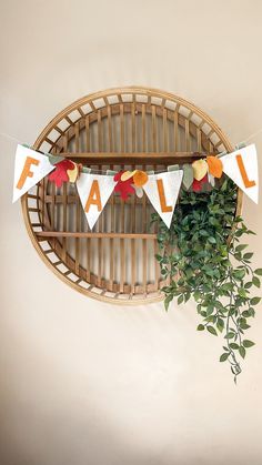 a plant is sitting in front of a wall hanging banner with the word fall on it