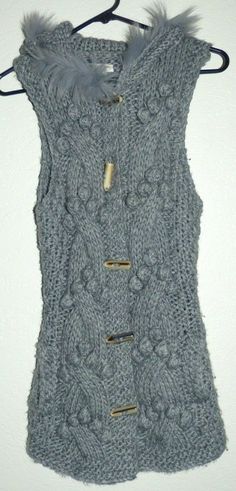 This listing is for a women's size medium/large COZY S&S Casual gray knit front button sleeveless cardigan sweater. This sweater features a hood trimmed in faux fur and front side pockets. The fabric is Acrylic/wool blend. It measures 17 inches across the armpits, 30 inches top of shoulder down to bottom in length. Excellent like new condition! No stains, fading, snags, pilling, or odors. All of my listings come from a smoke free/pet free home. I will ship out within 24 hours of receiving cleare Knitted Winter Vest, Winter Sweater Vest For Cold Weather, Winter Sleeveless Sweater Vest For Cold Weather, Sleeveless Sweater Vest For Winter, Chunky Knit Sleeveless Vest For Winter, Chunky Knit Sleeveless Winter Vest, Winter Chunky Knit Sleeveless Vest, Sleeveless Knit Sweater Vest For Winter, Knit Vest For Winter