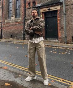 a man standing on the side of a road in front of a tall brick building