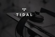 the logo for tidal is shown on top of a table with headphones and earbuds