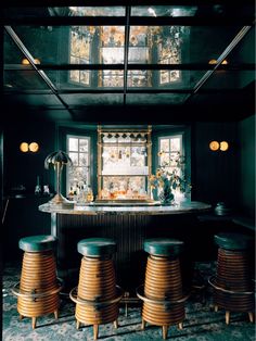 a bar with four stools in front of it and an open window behind it