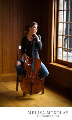 a woman sitting on top of a chair holding a cello