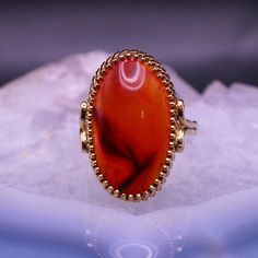 Don't miss out on this stunning vintage 14K yellow gold ring with a striking red agate cabochon at its center. The translucent agate has a rich reddish orange hue and a mystical moonstone-like shimmer. Known for its unique inclusions that resemble natural symbols, agate is a captivating member of the quartz family. This beautiful stone is elegantly set in a bezel setting, measuring around 23mm x 13.5mm. Sized at 9, this exquisite ring is marked with a 14K stamp and is in excellent vintage condit Gold Agate Cabochon Rings, Oval Cabochon Agate Ring With Polished Finish, Red Oval Agate Jewelry, Unique Orange Cabochon Ring, Vintage Orange Cabochon Rings, Reddish Orange, Agate Cabochon, Red Agate, Reddish Brown