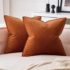 two brown pillows sitting on top of a white couch