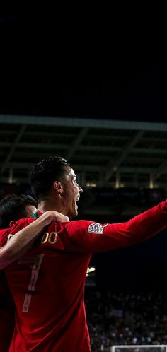 two men in red uniforms are playing soccer