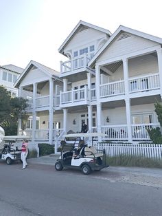 two golf carts parked in front of a large white building with balconies on the second floor