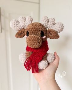 a hand holding a crocheted moose stuffed animal