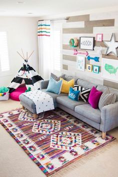 a living room filled with lots of colorful pillows and blankets on top of a rug