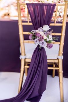 a chair with purple draping and flowers on the back is set up for a wedding