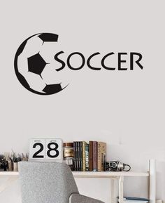 a soccer ball is on the wall next to a chair and bookshelf in a room