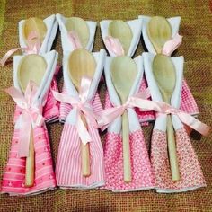 six wooden spoons with pink and white designs are lined up on a brown cloth