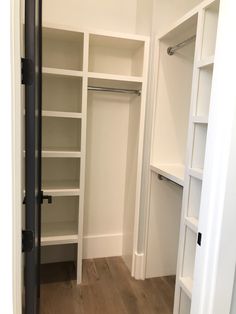 an empty walk in closet with white shelving