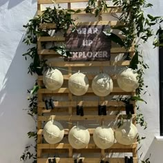 a wooden pallet filled with lots of white umbrellas hanging from it's sides