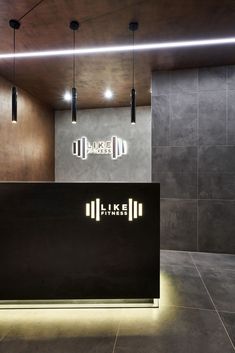 the front desk of an office with modern lighting and concrete walls, along with black tile flooring