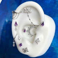 a pair of ear piercings with amethyst stones on them sitting in a blue bowl