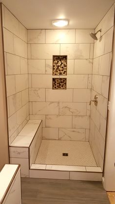 a walk in shower sitting next to a white sink and counter top under a light